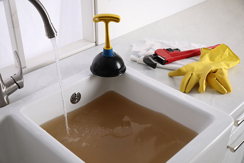 Clogged Kitchen Sink Backed Up With Dirty Water clogged kitchen sink filled with dirty standing water and plunger