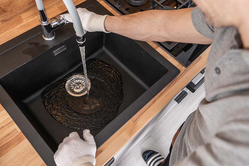 Drain Cleaning Black Kitchen Sink Buildup Removal plumber cleaning black kitchen sink drain with heavy buildup