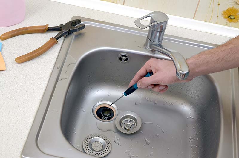 Drain Cleaning Black Kitchen Sink Buildup Removal plumber cleaning black kitchen sink drain with heavy buildup