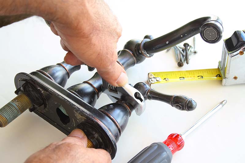 Plumber Disassembling Bronze Faucet for Repair plumber disassembling bronze two handle faucet for repair