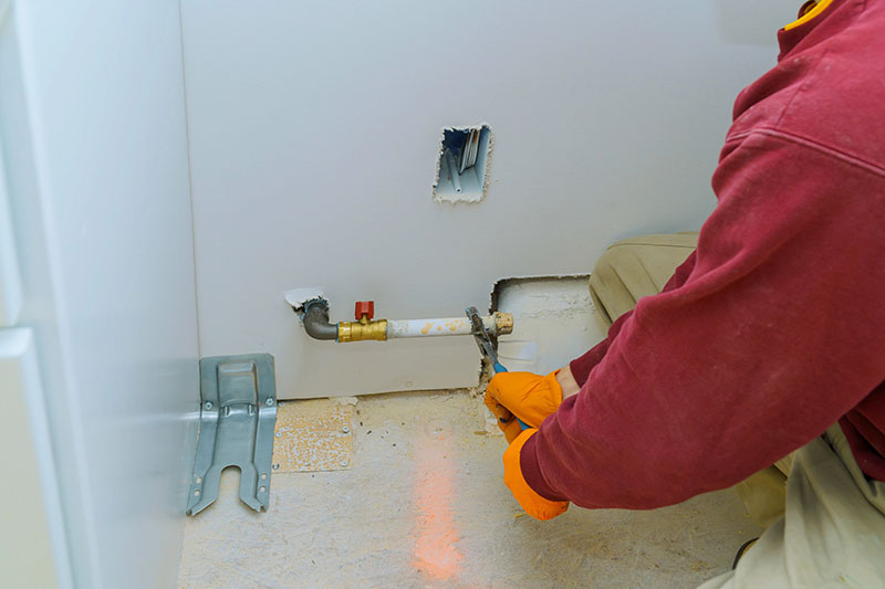 Plumber Repairing Gas Line Valve Inside Wall Opening plumber in gloves repairing gas line shut off valve inside wall opening