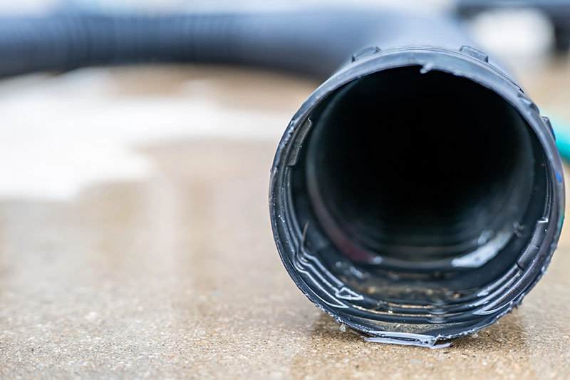 sump pump discharge pipe inspected during repair service with water on ground