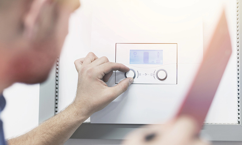 Technician Commissioning Tankless Water Heater Controls technician adjusting tankless water heater digital controls during installation