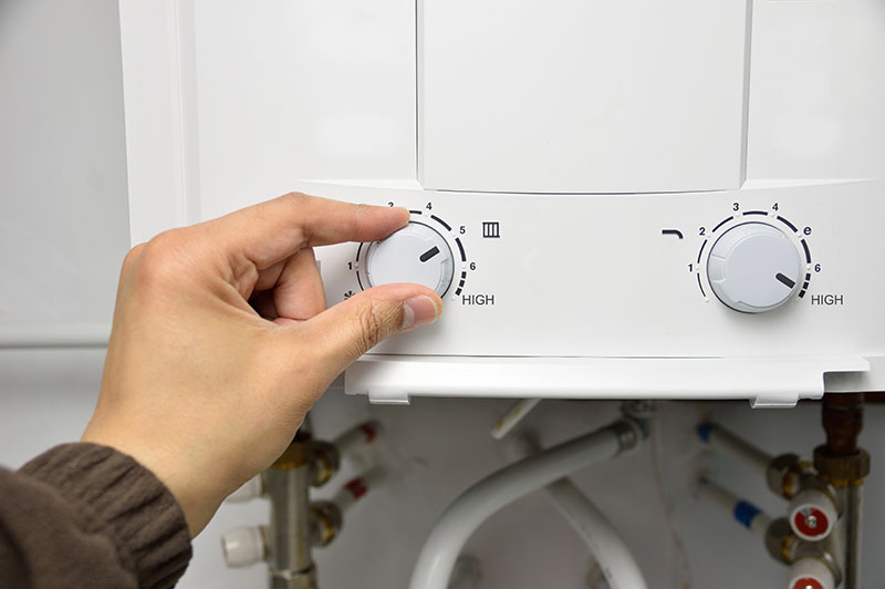 hand adjusting flow and temperature dials on tankless water heater unit