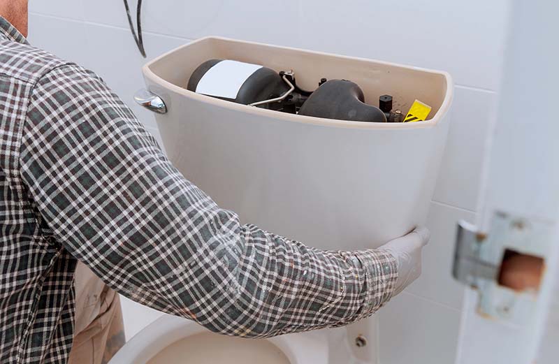 Plumber Placing Tank Onto Bowl During Toilet Installation plumber placing toilet tank onto bowl during installation