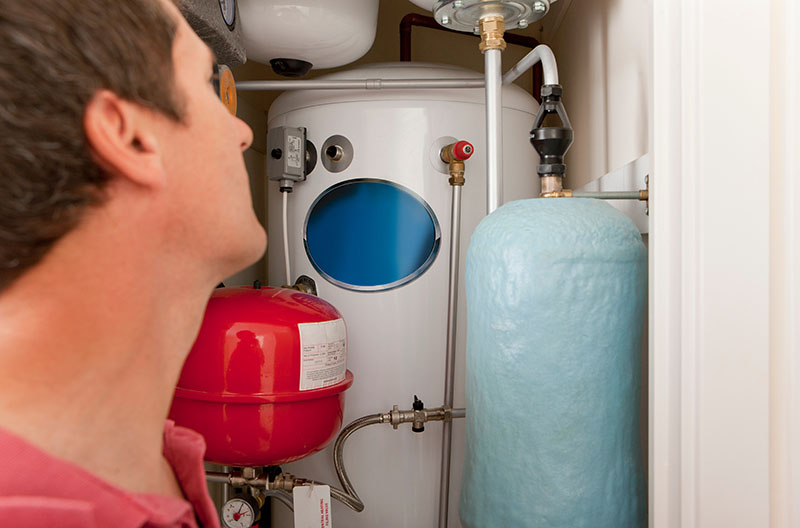 technician checking water heater unit controls and warning labels